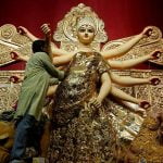 An artisan adorns a gold saree, a traditional Indian women cloth, on an idol of Hindu goddess Durga, at a temporary platform called pandal, ahead of the Durga Puja festival in Kolkata