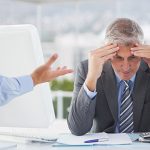 Frustrated businessman sitting with hands on forehead