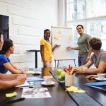 Graphic designers discussing on whiteboard with their colleagues