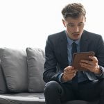 Shocked Young Businessman Looking at Tablet