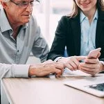 Smiling businesswoman showing phone to colleague