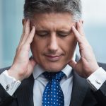 Portrait of stressed businessman touching his head