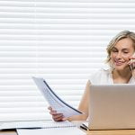 Beautiful woman talking on mobile phone while holding document