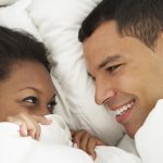 Couple Relaxing In Bed Wearing Pajamas