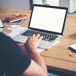 man hands typing working with laptop on wooden desk.