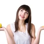 Young woman choosing between apple and cake