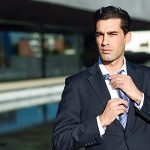 Young handsome businessman adjusting a tie in urban background