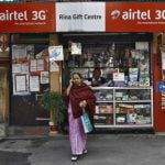 A woman speaks on her mobile phone after recharging it at a local stationary cum prepaid mobile recharge shop in Kolkata